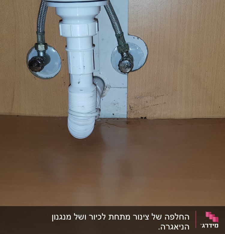 צינור ניקוז לבן מתחת לכיור בארון עץ
